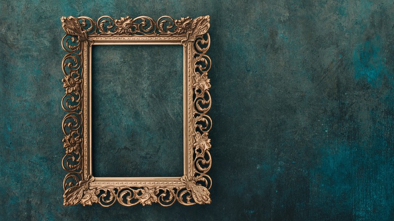 A vintange bronze picture frame, empty, hanging on a wall