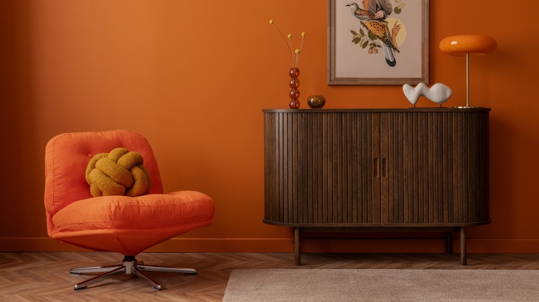 Shot of room with vintage chair, side table, lamp, decor, and artwork