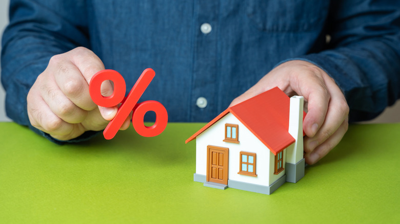 house and percentage figures in a person's hands
