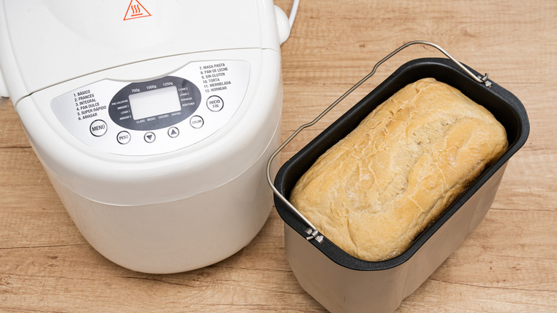 A bread machine with a loaf of bread next to it