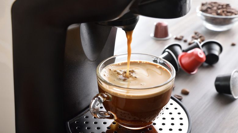 And espresso machine emptying coffee into a clear glass mug