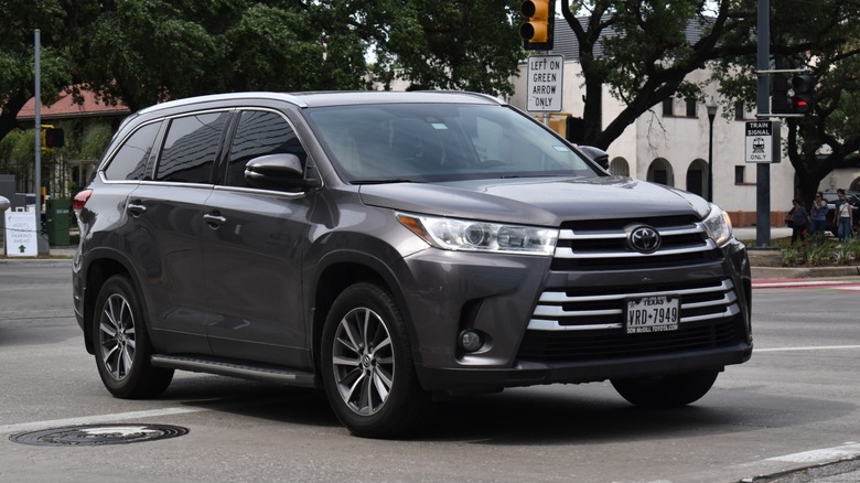 A grey Toyota Highlander SUV driving on a street.