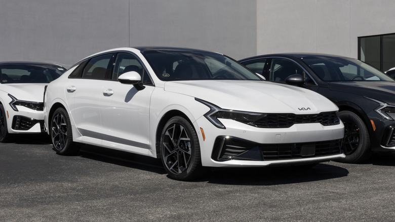 A white Kia K5 EX FWD Sedan at a dealership.