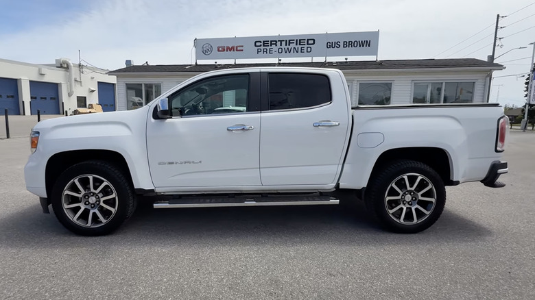 A white 2021 GMC Canyon Denali Crew Cab parked outside of a dealership