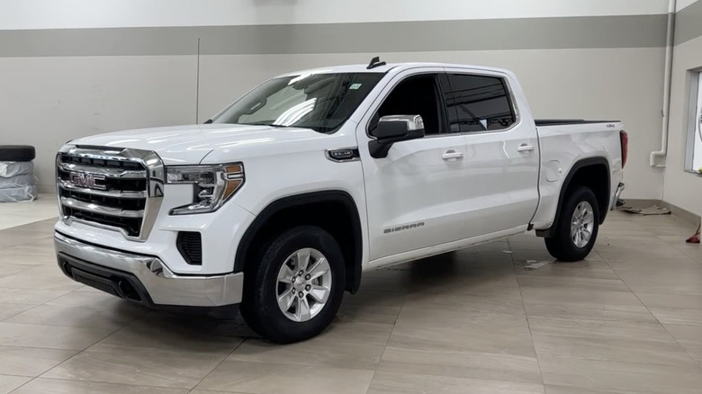 A white 2021 GMC Sierra 1500 SLE Crew Cab on display in a white showroom.