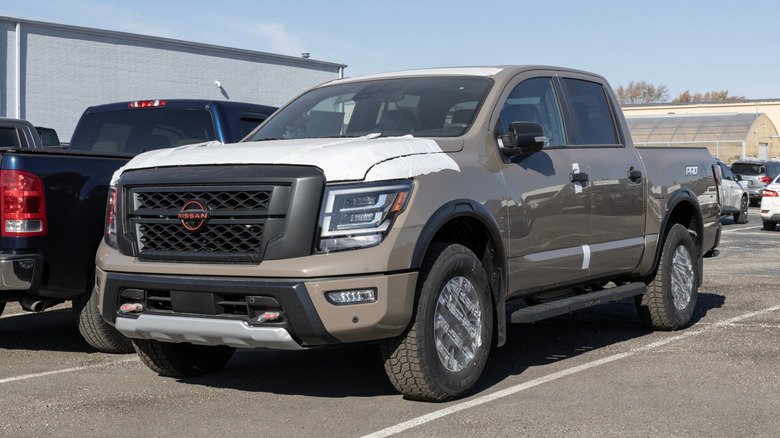 A brown Nissan Titan freaturing a crew cab on display in a dealership parking lot
