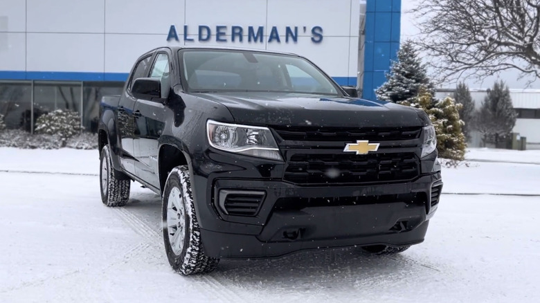 A black 2022 Chevrolet Colorado LT Crew Cab parked outside of a dealership in the snow