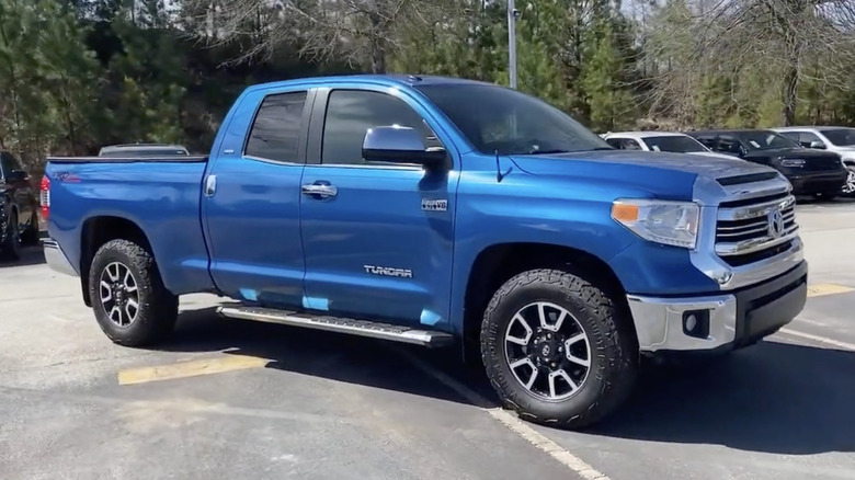 A blue 2017 Toyota Tundra parked in front of a line of other trucks on a sunny day
