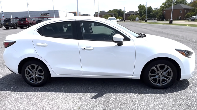 A side view of a white 2020 Toyota Yaris parked in a dealership parking lot