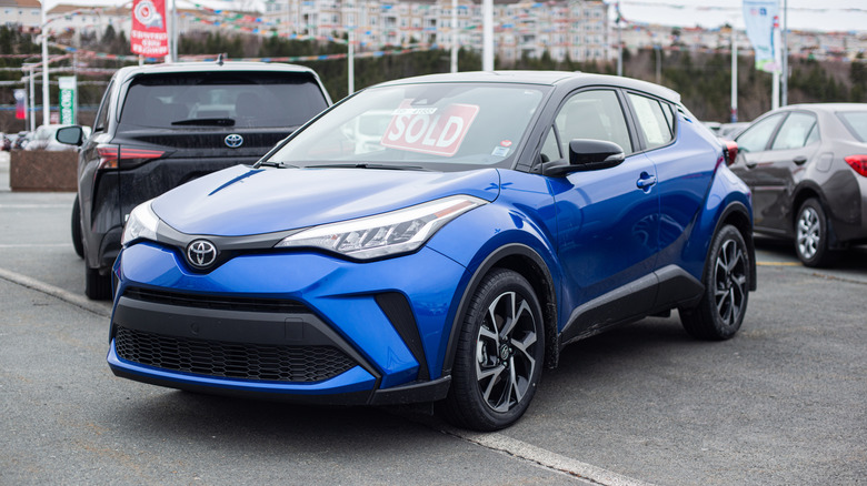 A blue 2021 Toyota C-HR parked at a dealership with a 'Sold' sign behind the windshield