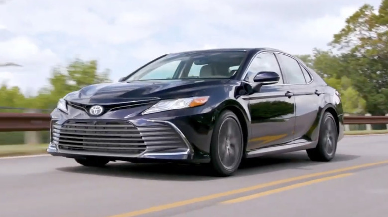 A black 2021 Toyota Camry on a scenic road