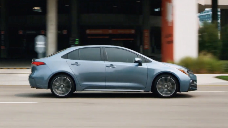 A side view of a blue 2022 Toyota Corolla driving through a city