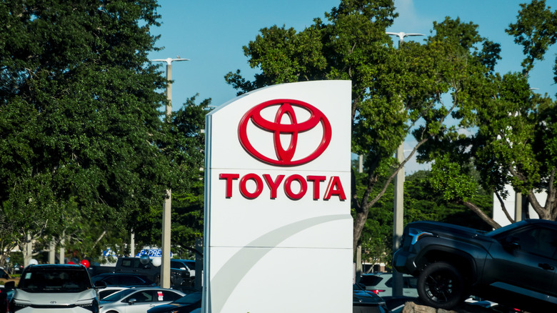 The sign for a Toyota dealership displayed in a crowded parking lot