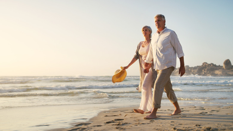 Older couple walking on the beach watching a sunset