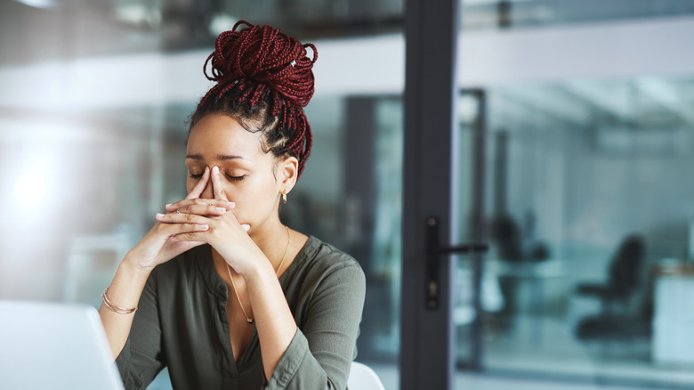 A young woman sitting in an office looking stressed.