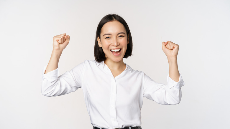 Smiling professional young woman with her arms raised enthusiastically.