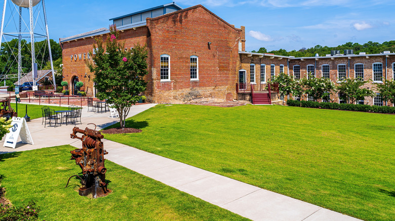 An exterior shot of the Rocky Mount Mills shopping center featuring a small grassy park and a water tower