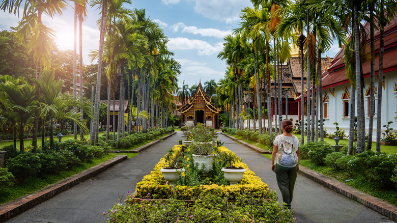 Woman walking towards Thai temple in Chiang Mai, Thailand