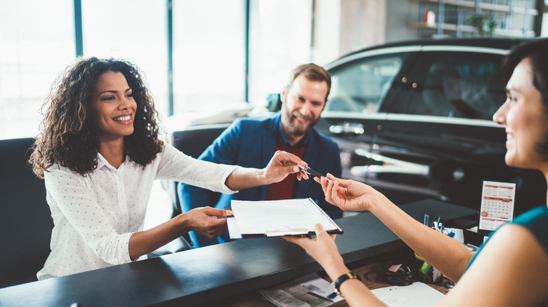 A smiling couple at a car dealership