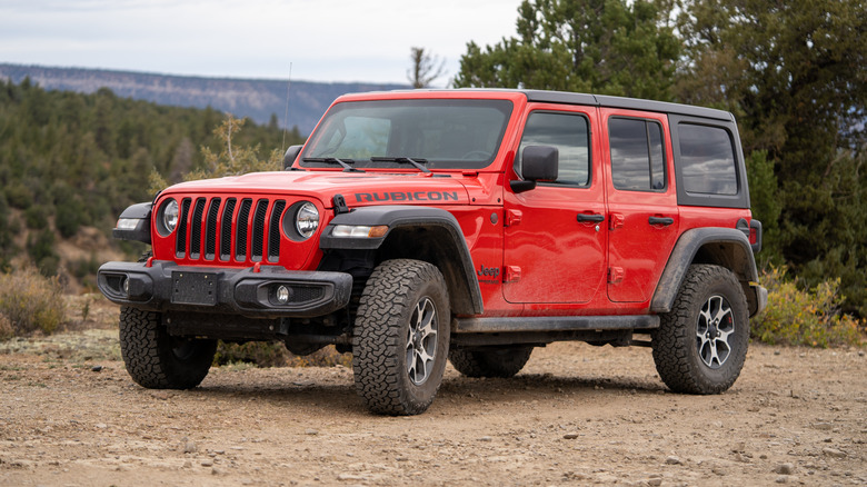 Red Jeep Wrangler 4-Door Rubicon parked on dirt road in Colorado.