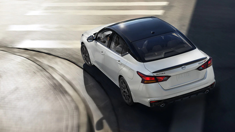 white 2026 Nissan Altima with black trim makes left turn on city street