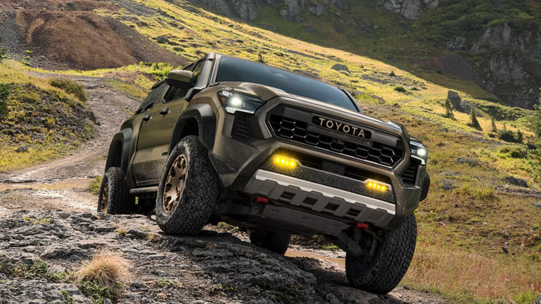 dark 2026 Toyota Tacoma with fog lights on climbing a rock