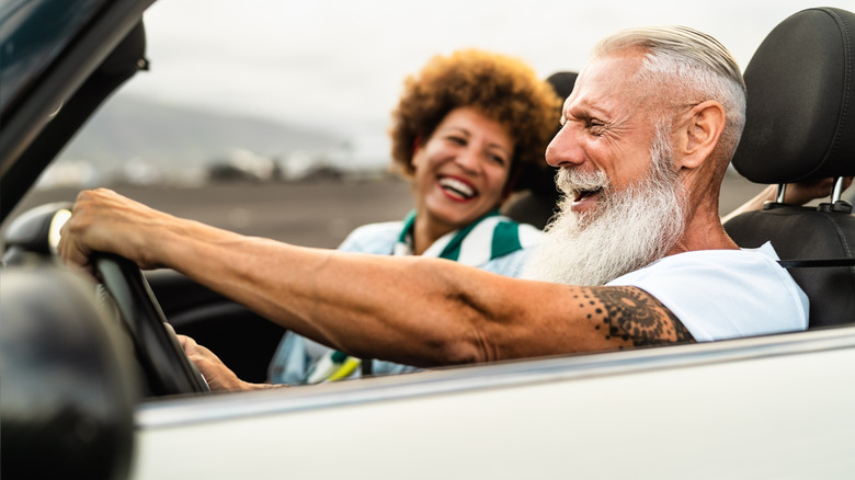A mature couple having fun in a convertible car.