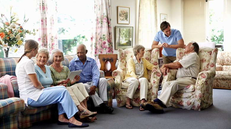 Seniors sitting on sofas while talking to staff in a retirement home.