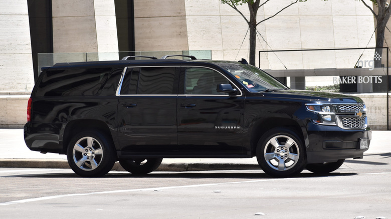 A black Chevy Suburban SUV cruising in a financial district.