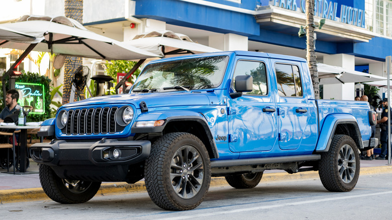 Blue Jeep Gladiator parks on a city street.