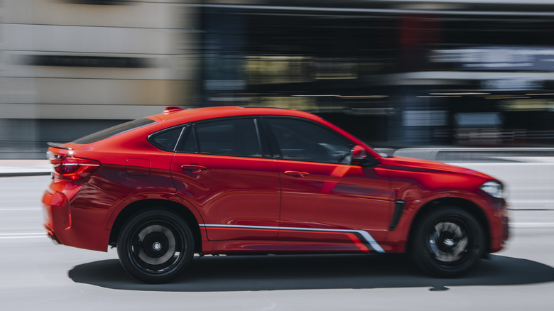 Red BMW X6 M car moving on the street.