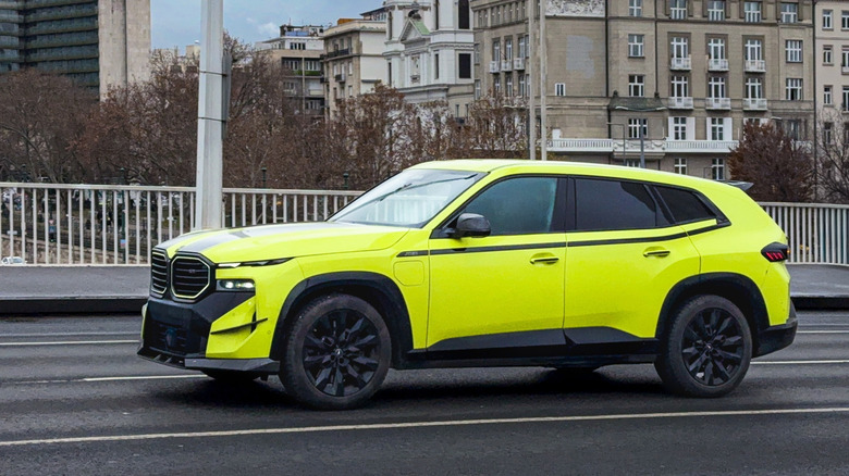 A bright yellow BMW XM driving on a bridge.