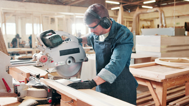 Someone woodworking with a miter saw