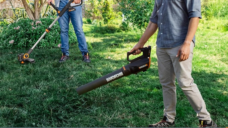 two people using the Worx trimmer and leaf blower in a yard