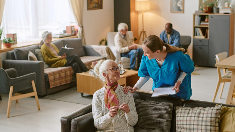 High angle shot of nurse communicating with senior woman who sharing progress in crocheting.