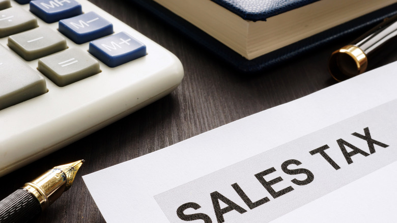 A piece of paper with the words sales tax on a desk with a calculator.