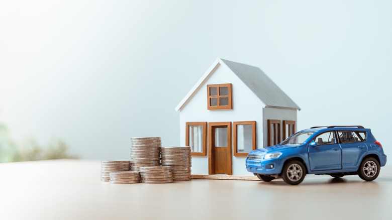 Model house, car, and stacked coins representing property insurance.