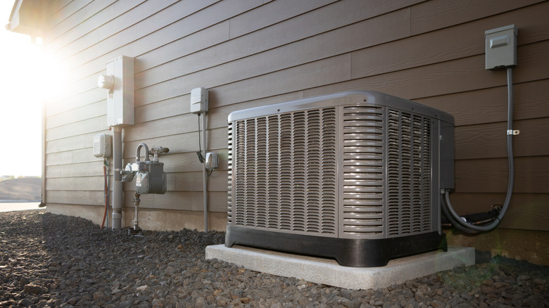 Modern HVAC air conditioner unit on concrete slab outside of duplex house.