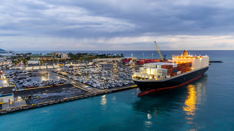 A bustling harbor in Honolulu, Hawaii, with a docked container ship unloading cargo.
