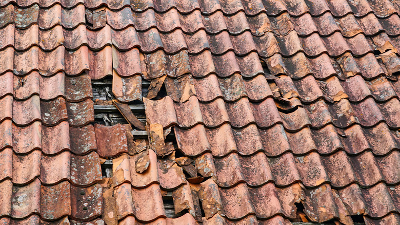 Dangerously damaged and missing clay tile on a historic house's roof
