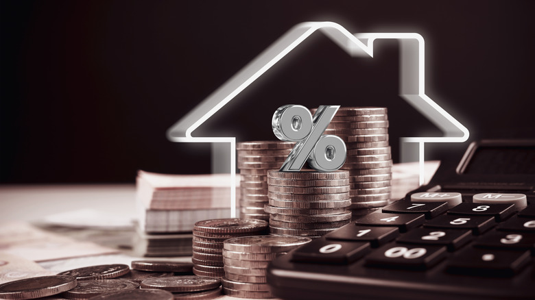 Stack of coins and calculator with house lines and percentage symbol.