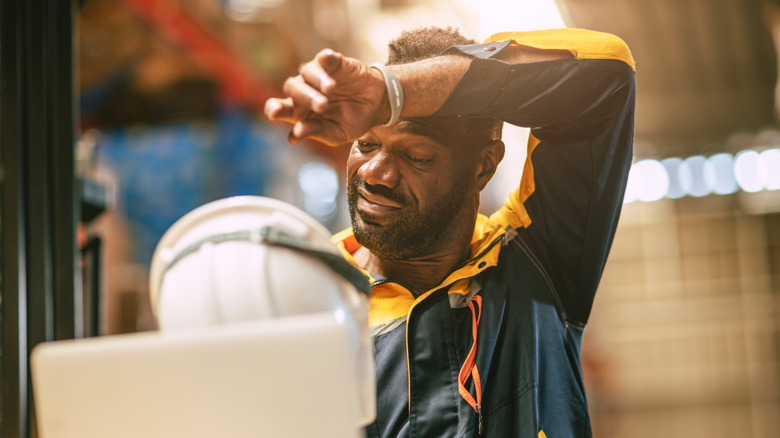 African black male worker tired stressed sweat from hot weather in summer working indoor warehouse building.