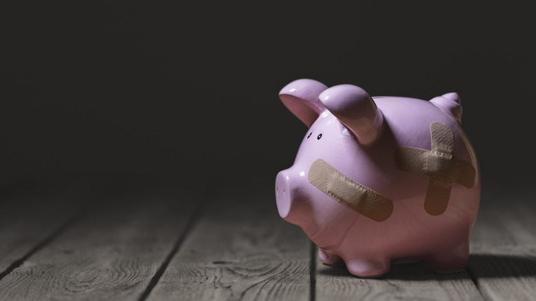 Broken piggy bank with band aid bandage or plaster finance background concept for economic recession or bankruptcy.