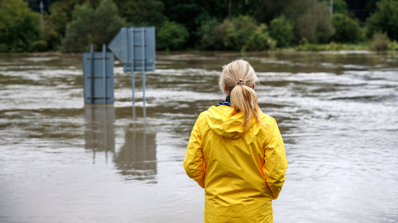 Worried woman looking at overflowing water during flood.