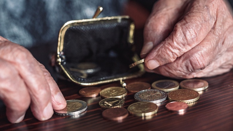Close up of elderly hands placing coins into a coin purse
