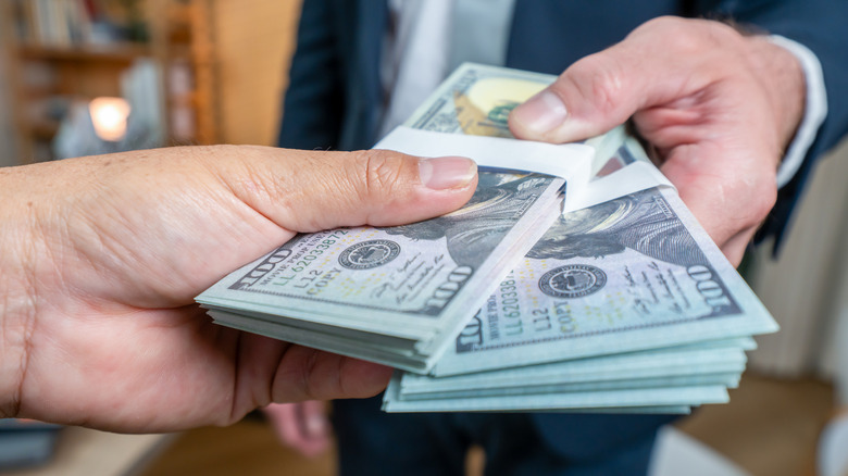 hands passing stacks of dollars