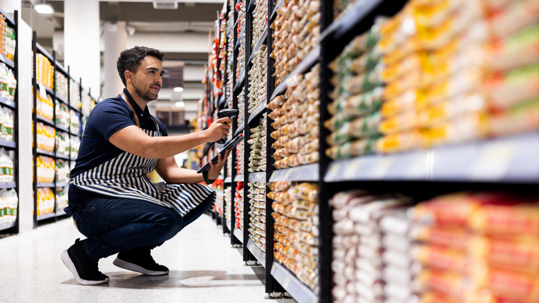 grocery worker scanning items on shelves