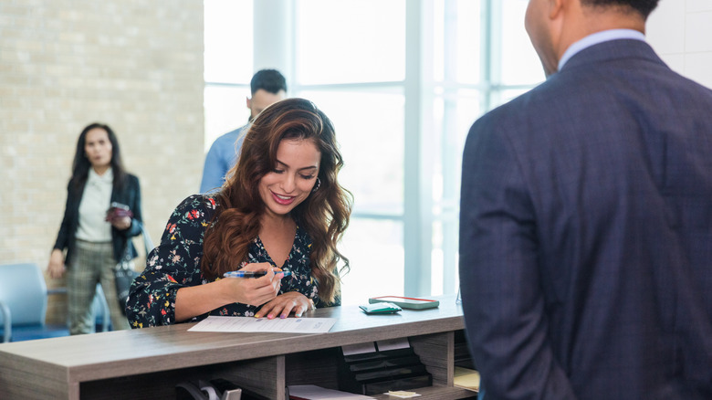 Woman filling out form with bank teller.