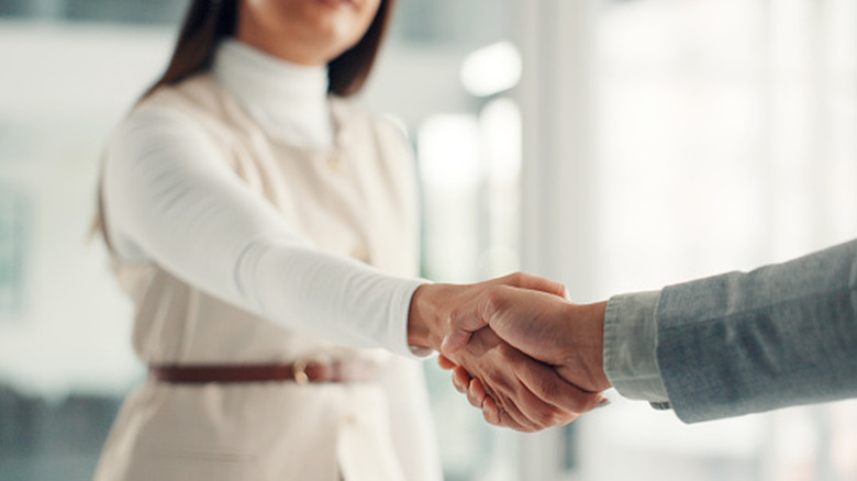 A professional woman shaking hands with another person.