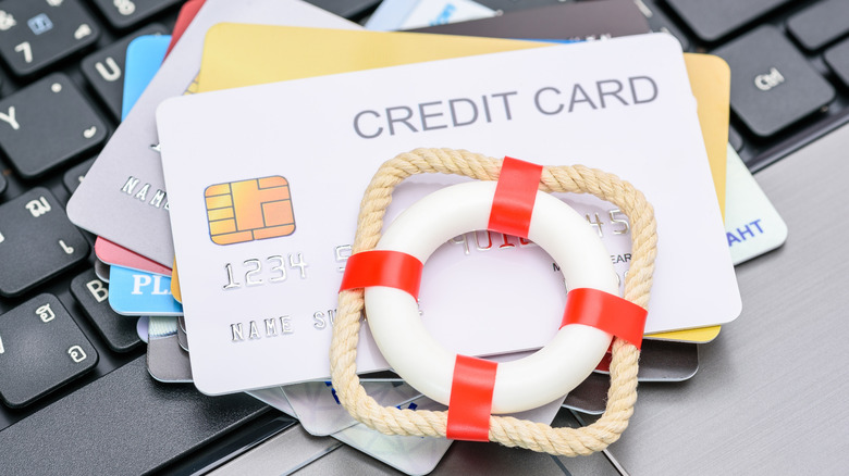 Red lifebuoy or lifebelt atop a stack of credit cards on a laptop.